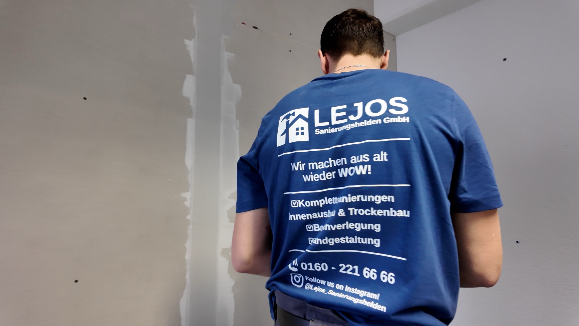 Monteur in LEJOS-Arbeitskleidung vor einer frisch gespachtelten Wand